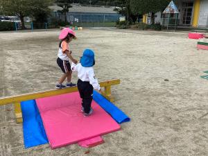 平均台を渡る年少児の手を引く画像