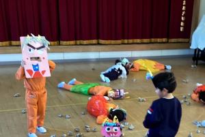 豆まきでやられたと倒れこむ年長児の画像