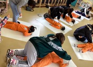 模造紙の上に寝転がり体の形を描く画像