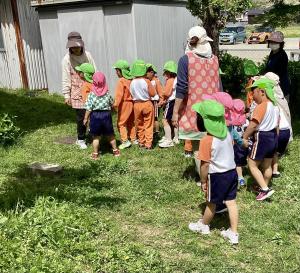 年長児が年少児を園庭探検に連れて行く画像